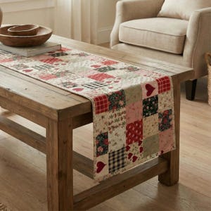 Könnte beinhalten: Ein Patchwork-Tischläufer mit Herz-, Blumen- und Vichy-Mustern in Rot, Rosa und Creme. Der Läufer liegt auf einem Holztisch. Auf dem Tisch befindet sich auch eine Holzschale. Der Läufer ist aus Stoff.