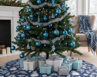 Puede incluir: Un árbol de Navidad decorado con adornos azules, oropel plateado y una falda de árbol con estampado azul y blanco. Debajo del árbol hay regalos envueltos en cajas blancas, plateadas y azules. La escena está ambientada en una habitación bien iluminada.