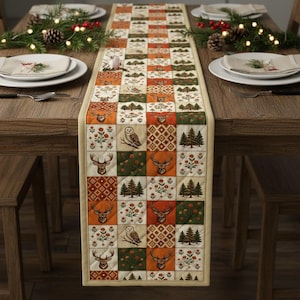 May include: A quilted table runner with a patchwork design featuring deer, owls, trees, and floral patterns in shades of orange, green, and cream. The runner is placed on a wooden table set for a meal.
