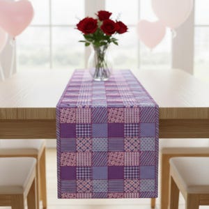 May include: A purple patchwork table runner with various patterns, including stripes, polka dots, and floral designs. The runner is placed on a wooden table, with a vase of red roses in the center. Heart-shaped balloons are in the background.