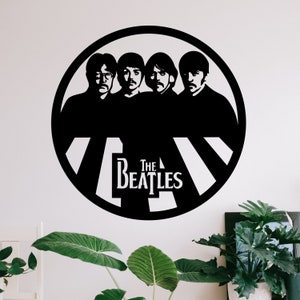以下が含まれることがあります： ビートルズのバンドメンバーをシルエットにした白黒の壁飾り。"The Beatles"の文字とシマウマの横断歩道のパターンが描かれている。