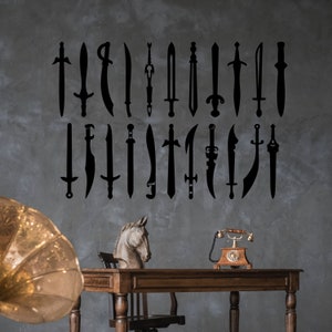 May include: A collection of black sword silhouettes arranged on a gray wall. The swords vary in design, with straight and curved blades. A wooden desk with a horse head sculpture and a vintage telephone are in the foreground.
