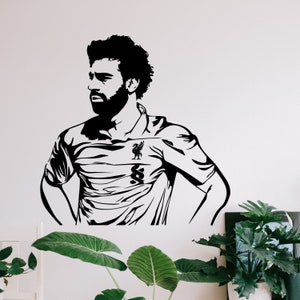 May include: Black and white silhouette of a soccer player wearing a jersey with a team logo. The player is standing with their hands on their hips.
