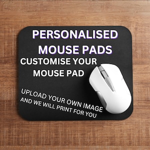 May include: A black mouse mat with the text "PERSONALISED MOUSE PADS CUSTOMISE YOUR MOUSE PAD UPLOAD YOUR OWN IMAGE AND WE WILL PRINT FOR YOU" in white text. A white computer mouse is on the mouse mat.