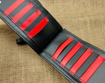May include: A black leather bifold wallet featuring alternating red and black vertical card slots on both interior panels. The wallet includes silver-toned metal snap fasteners at the corners and a zippered compartment along the top edge.