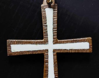 May include: A white enamel cross pendant with a brown metal frame. The cross has a textured edge and a loop at the top for hanging.