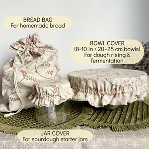 May include: A beige fabric bread bag, a small jar cover, and a large bowl cover, all featuring a botanical pattern of red and green berries on thin vines. The bowl cover is labeled for 8-10 inch bowls, while the jar cover is for sourdough jars.