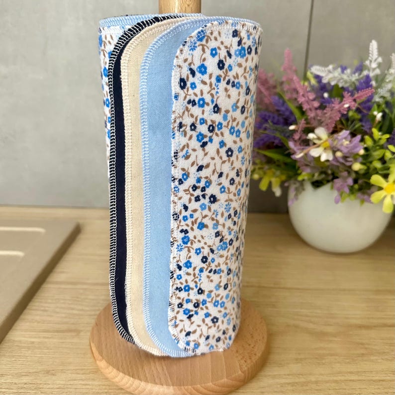 Cotton flannel unpaper towel roll with reusable paperless kitchen towels featuring a blue floral print on one side and coordinated solid colors on the reverse. Flannel naturally sticks to itself, so no buttons are needed to roll it up. Best stored wrapped around an empty paper towel roll. A practical farmhouse kitchen accessory and eco-friendly zero waste gift.