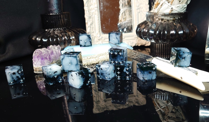 Pode incluir: Um conjunto de 10 dados preto e branco com um design nublado, semelhante a uma gal&aacute;xia. Os dados est&atilde;o espalhados sobre uma superf&iacute;cie preta com um reflexo dos dados vis&iacute;vel.