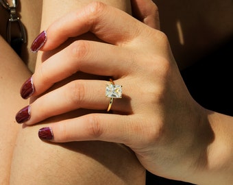 May include: A gold ring with a large, clear, rectangular-shaped diamond.