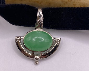 May include: A silver choker necklace with a green oval stone pendant. The pendant has a decorative silver frame.
