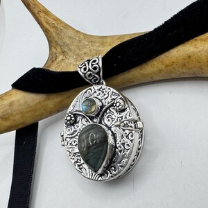 Puede incluir: Colgante de plata con un medall&oacute;n en forma de coraz&oacute;n de labradorita y un medall&oacute;n redondo m&aacute;s peque&ntilde;o de labradorita. El medall&oacute;n est&aacute; decorado con un intrincado dise&ntilde;o floral.
