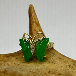 May include: A gold ring with a green jade butterfly design. The butterfly has clear rhinestones in the center.