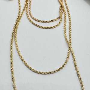 May include: A set of four gold rope chains of varying lengths. The chains are layered on top of each other and are hanging from a wooden antler.