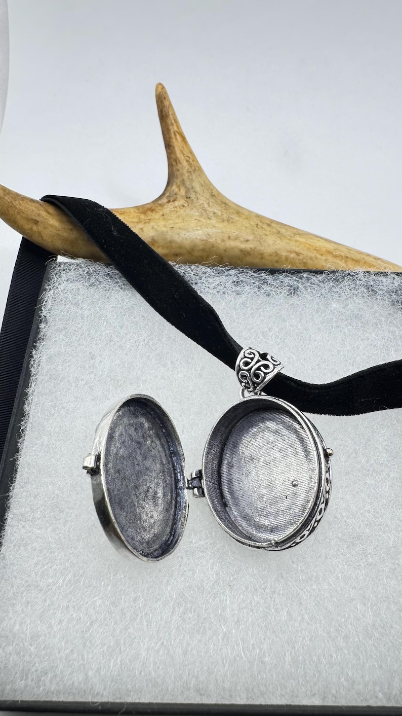 Puede incluir: Un collar con un medall&oacute;n de plata con un dise&ntilde;o ornamentado. El medall&oacute;n est&aacute; abierto, revelando un interior vac&iacute;o.