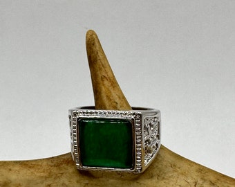 May include: A silver ring with a square green stone set in a decorative frame.