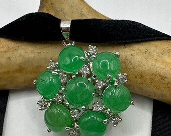 May include: A silver necklace with a green jade pendant. The pendant is made up of multiple round jade stones surrounded by small clear rhinestones.