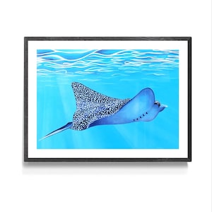 May include: A blue and white spotted ray swims in a turquoise blue ocean. The ray has a long, thin tail and a large, flat body. The ocean is calm and clear, with sunlight shining through the water.