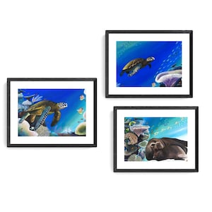 May include: Three framed paintings depicting underwater scenes. The top painting shows a sea turtle swimming in blue water with coral and fish. The middle painting shows a sea turtle swimming in blue water with coral and fish. The bottom painting shows a sea lion resting on a coral reef.