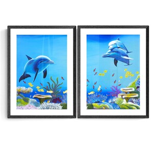 May include: Two framed paintings of dolphins swimming in a blue ocean with coral reefs and colorful fish. The paintings are in black frames.