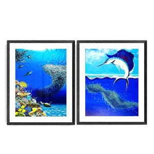May include: Two framed prints of underwater scenes. The left print shows a coral reef with a school of fish swimming around a sea turtle. The right print shows a blue marlin jumping out of the water with a school of fish below.