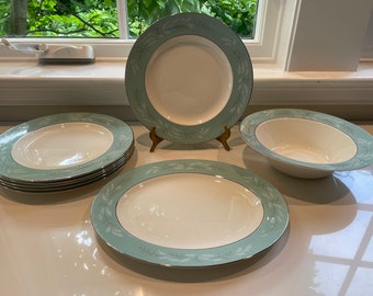 May include: Set of five white ceramic plates with a green and white floral design. The plates include a large oval platter, two soup bowls, and two dinner plates.