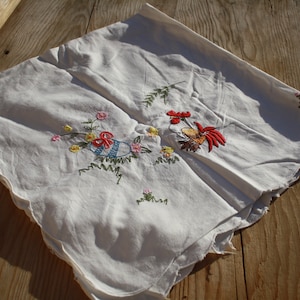 May include: White linen tablecloth with embroidered flowers and a rooster design. The embroidery is in shades of red, yellow, blue, and green.