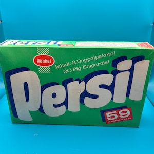 Könnte beinhalten: Eine grüne Schachtel mit weißer Aufschrift "Persil" und "Henkel". Die Schachtel hat einen roten Aufkleber mit der Aufschrift "Inhalt: 2 Doppelpakete! 20 Pfg Ersparnis!" und "59".
