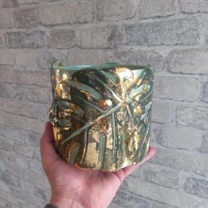 Vaso de planta monstera verde e dourado