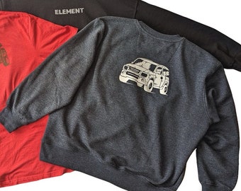 May include: Three different clothing items: a red t-shirt with a brown car graphic, a gray sweatshirt with a brown car graphic, and a black hoodie with the word "ELEMENT" printed on the front.