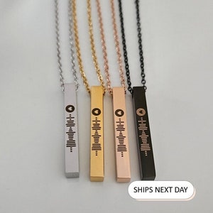 Op de afbeelding: Vier kettingen met een staafje met verschillende kleuren kettingen en een gegraveerde muzieknoot op elk staafje. De kettingen zijn zilver, goud, roségoud en zwart.