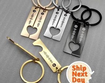 May include: Set of three matching keychains with a heart-shaped cutout and a music wave pattern. Each keychain has a different color: gold, silver, and black. The keychains are attached to a bottle opener.