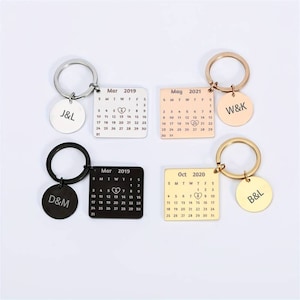 Puede incluir: Cuatro llaveros con dijes de calendario personalizados y etiquetas redondas de metal. Los dijes presentan un calendario con un símbolo de corazón en la fecha. Las etiquetas están grabadas con iniciales. Los llaveros son de color negro, dorado, plateado y dorado rosa.