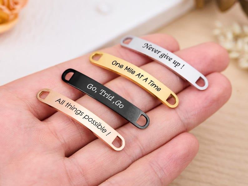 May include: Four metal shoe tags in rose gold, gold, black, and silver. Each tag has a different motivational phrase: "All things possible!", "Go, Trid, Go", "One Mile At A Time", and "Never give up!"