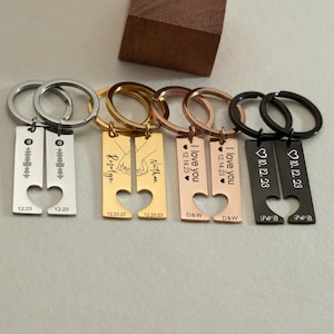 May include: Set of four matching couples keychains with heart-shaped cutouts. Each keychain features a different design, including a song lyric, a hand-holding couple, a name, and the phrase "I love you". The keychains are made of metal and come in silver, gold, rose gold, and black.