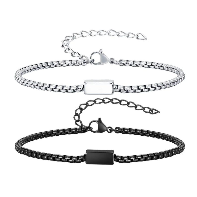 May include: Two stainless steel bracelets. One is silver-toned, the other is black. Each features a rectangular accent piece and a chain-link design. Both have adjustable clasps for a comfortable fit. These bracelets are suitable for everyday wear.