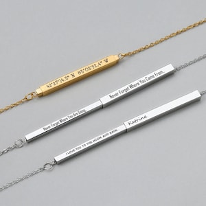 Puede incluir: Tres collares de oro y plata con barras grabadas. Las barras tienen el siguiente texto: "42°27'14.3" N 83°03'52.4" W", "Nunca olvides a dónde vas", "Nunca olvides de dónde vienes...", "Te amo hasta la luna y de regreso", y "Katrina".