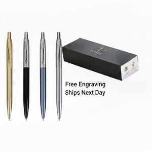 May include: Four pens in gold, black, blue, and silver, with a black presentation box. The pens have a streamlined design with silver detailing. The box is black with gold lettering and a logo.