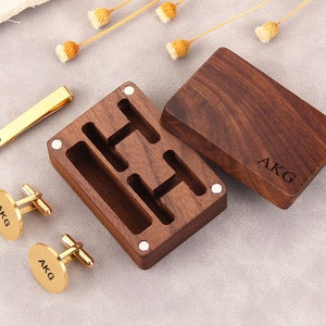 May include: A wooden box with a hinged lid, engraved with the initials "AKG". The box contains two gold cufflinks and a gold tie bar, all engraved with the same initials.