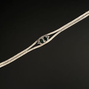 May include: A silver bracelet with a double row of clear stones and a centrepiece of three green stones.
