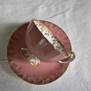 Peut inclure: Un service &agrave; th&eacute; rose vintage. La tasse et la soucoupe sont rose clair avec des bordures dor&eacute;es et un motif floral d&eacute;licat. La tasse a une anse incurv&eacute;e et repose sur une soucoupe assortie.