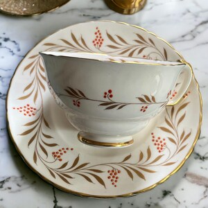 Pu&ograve; includere: Servizio da t&egrave; color crema con bordi dorati e un motivo decorativo di foglie marroni e bacche rosse. La tazza da t&egrave; &egrave; appoggiata sul piattino abbinato, creando un aspetto classico ed elegante. Un'aggiunta perfetta a qualsiasi collezione di servizi da t&egrave;.