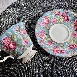 K&ouml;nnte beinhalten: Ein blaues und wei&szlig;es Tee-Set mit Blumenmuster. Die Tasse hat einen Henkel und einen ausgestellten Rand. Die Untertasse hat einen gewellten Rand.