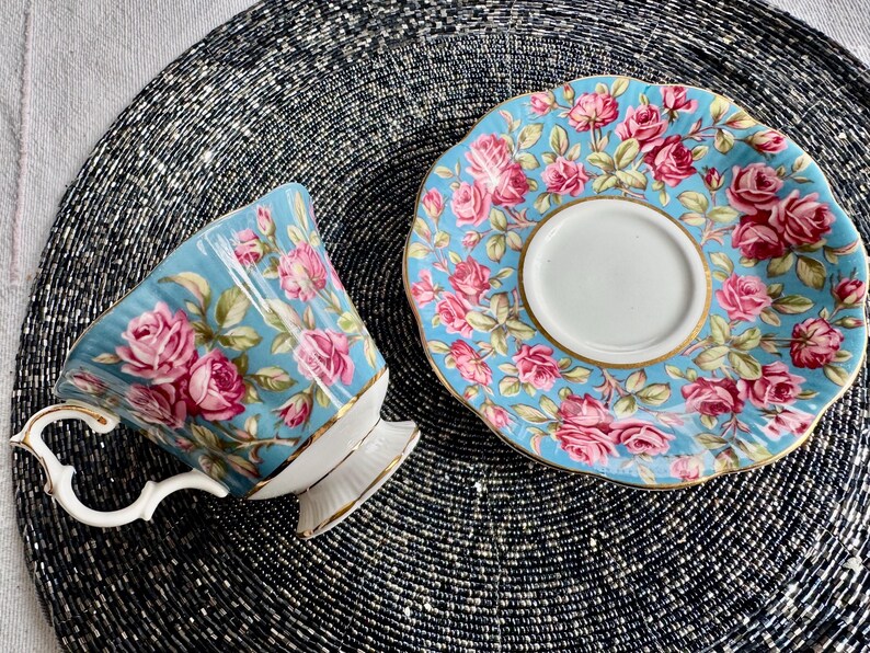 K&ouml;nnte beinhalten: Ein blaues und wei&szlig;es Tee-Set mit Blumenmuster. Die Tasse hat einen Henkel und einen ausgestellten Rand. Die Untertasse hat einen gewellten Rand.