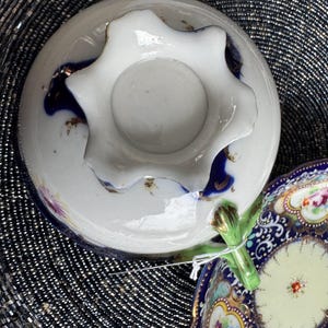 以下が含まれることがあります： 青と白の花柄のヴィンテージティーカップとソーサーのセット。ティーカップは波状の縁と緑色のハンドルが付いています。ソーサーは花柄がマッチしています。