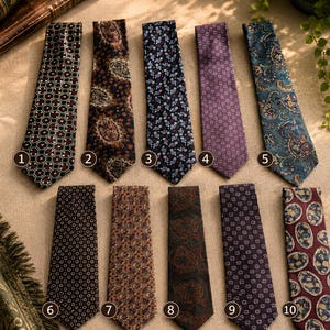 May include: A collection of ten neckties arranged in two rows, each featuring distinct patterns including geometric shapes, floral motifs, and paisley designs in various colors such as navy, burgundy, purple, and teal, labeled with numbers one through ten.