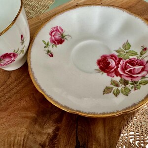 Pu&ograve; includere: Un set da t&egrave; bianco con bordo dorato e un motivo floreale di rose rosa.