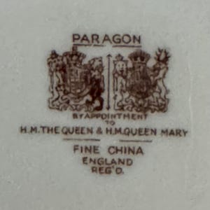 May include: A brown and white Paragon fine china stamp with the text "By Appointment to H.M. The Queen & H.M. Queen Mary" and "Fine China England Reg'd."