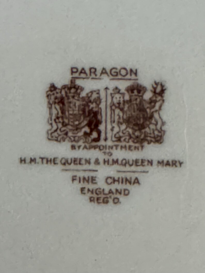 May include: A brown and white Paragon fine china stamp with the text "By Appointment to H.M. The Queen & H.M. Queen Mary" and "Fine China England Reg'd."