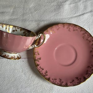 Peut inclure: Service &agrave; th&eacute; rose avec une tasse et une soucoupe. La tasse cannel&eacute;e est orn&eacute;e de dorures sur le bord et la poign&eacute;e. La soucoupe rose pr&eacute;sente un motif floral dor&eacute;. Un service &agrave; th&eacute; classique.